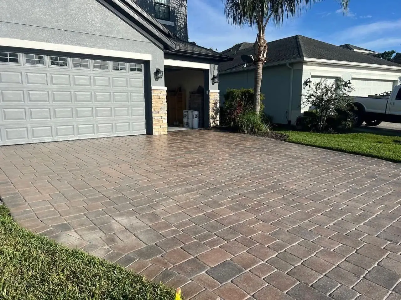 A paver driveway beside the garage, edged against the lawn