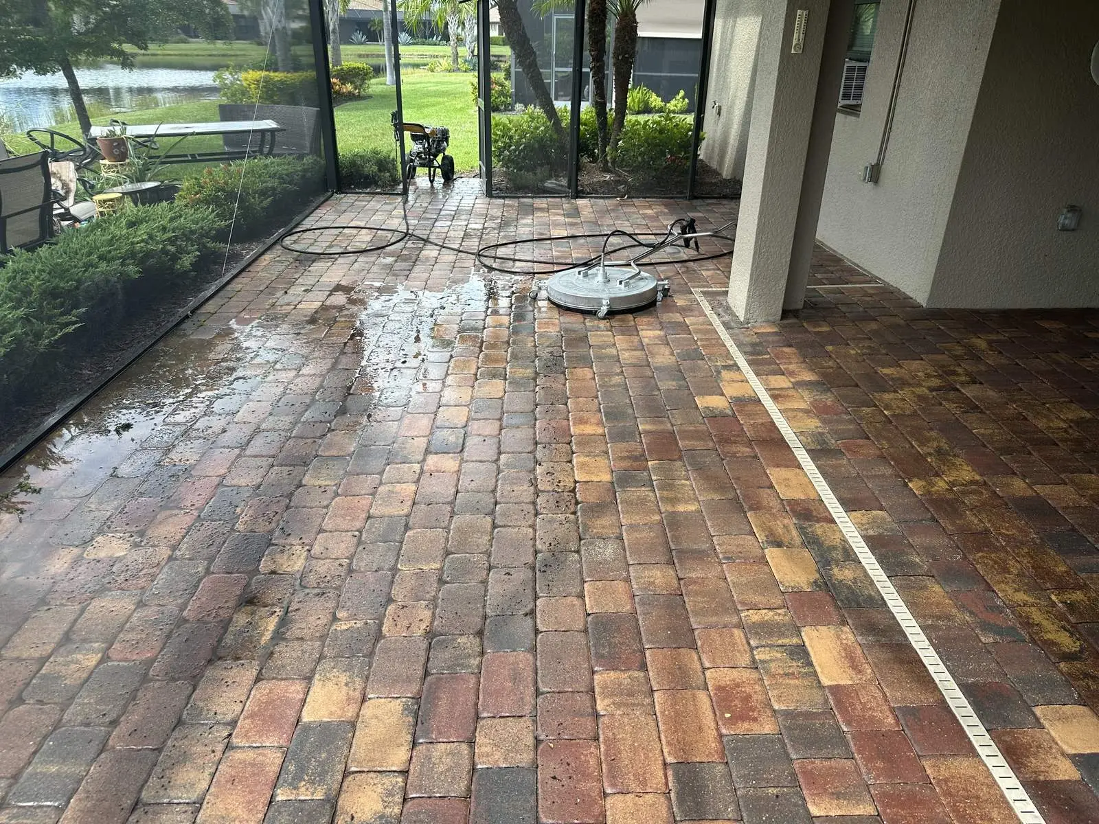 A lanai part way through cleaning, washed pavers on one side and stained pavers on the other