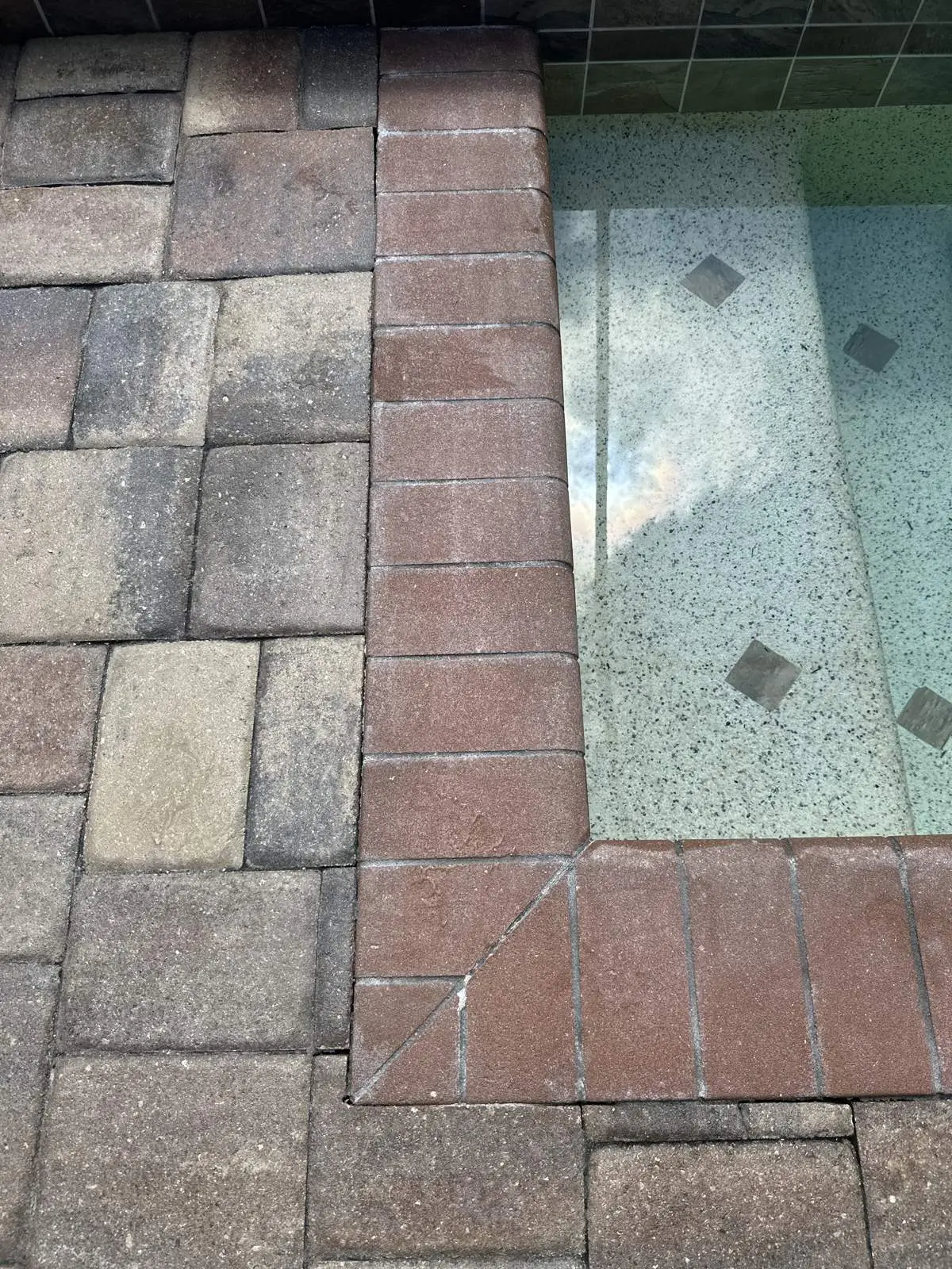 Cloudy patches of old sealer on the pavers beside the spa
