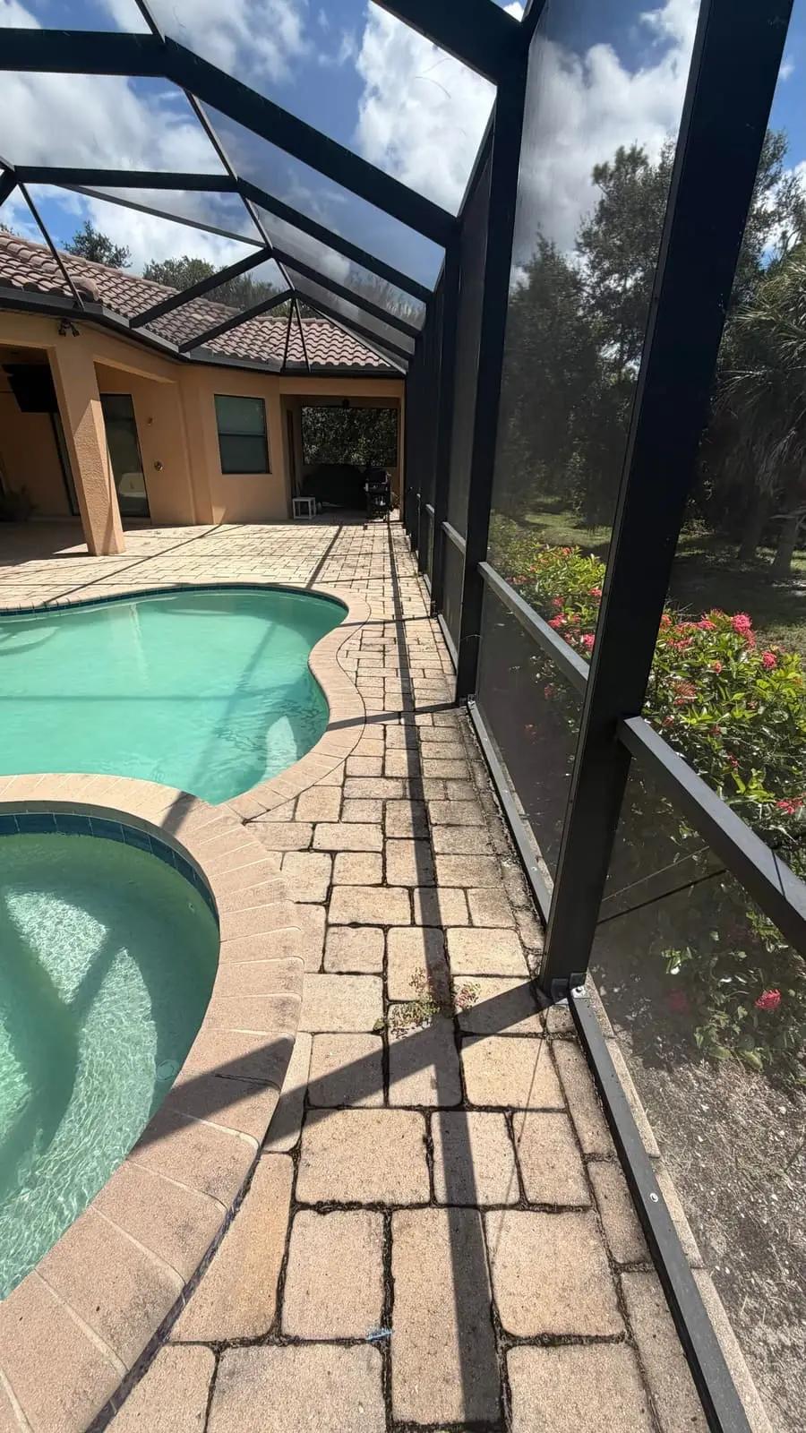 Weathered pavers with darkened, open joints around a pool